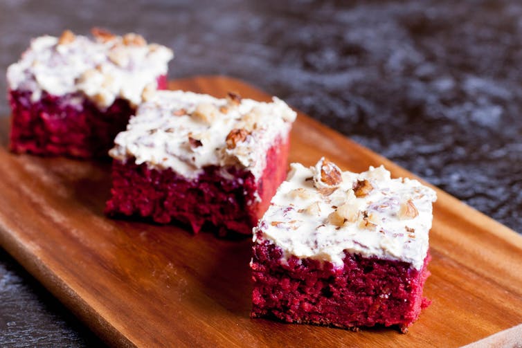 Three squares of beetroot/chocolate cake with white icing and nuts sprinkled on top