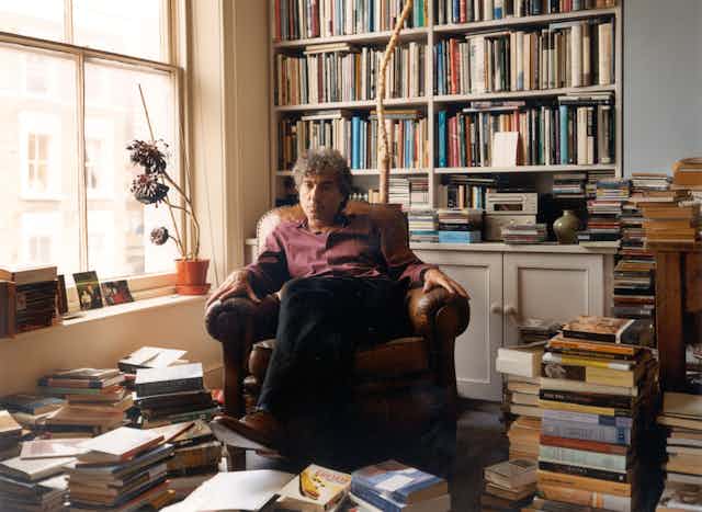 Adam Phillips sits in an armchair in his book-filled office.