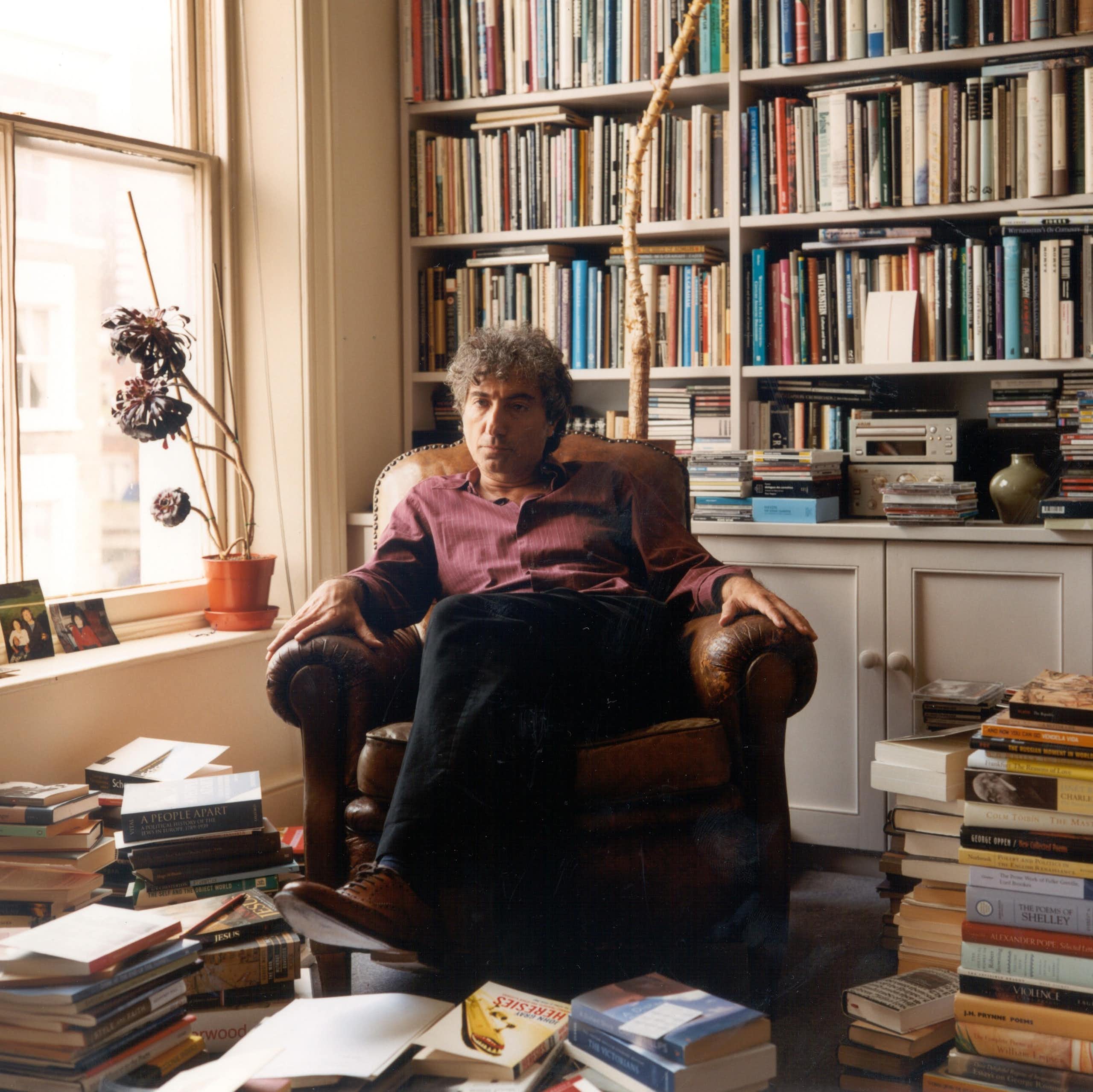 Adam Phillips sits in an armchair in his book-filled office.