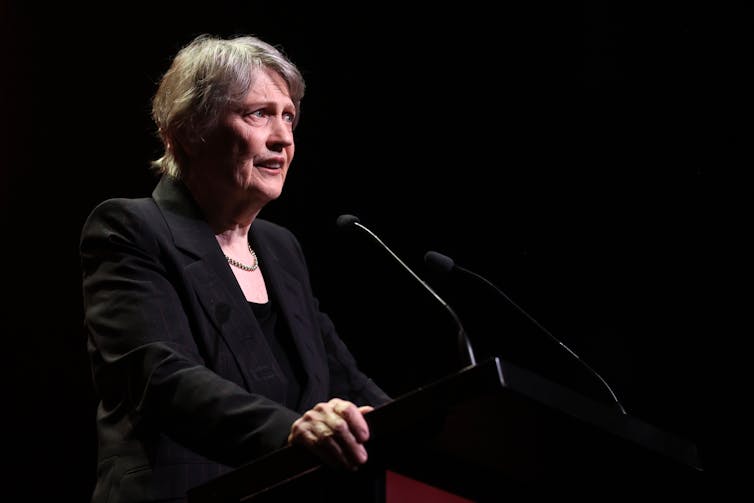 Helen Clark standing in front of a microphone