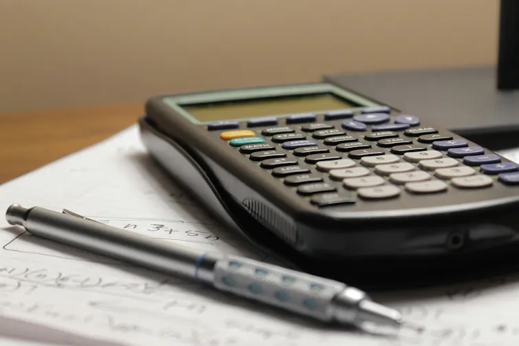 A calculator and pen rest on a notebook.