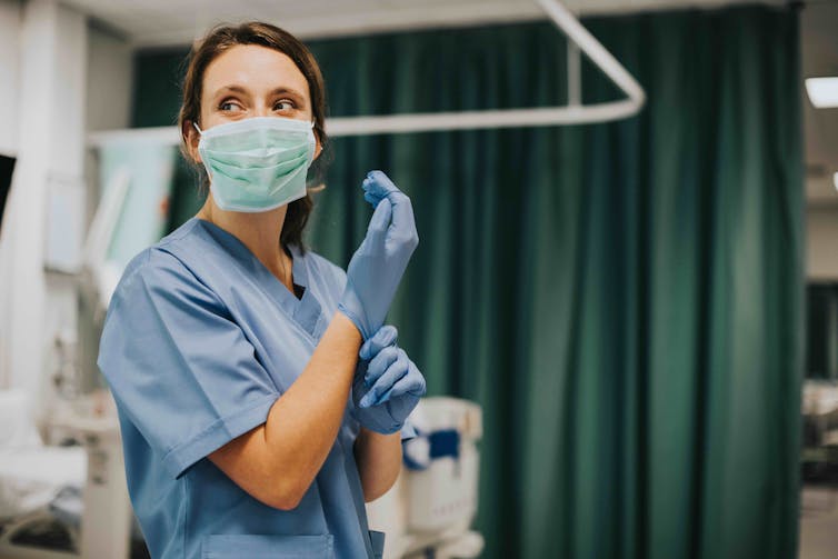 A nurse putting on gloves.