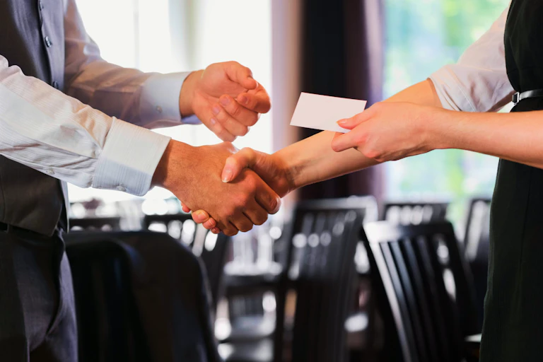 Business people shaking hands after meeting and changing cards in restaurant