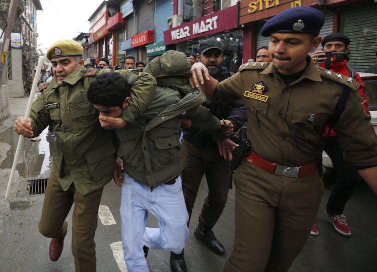 A Kashmiri man is arrested by police.