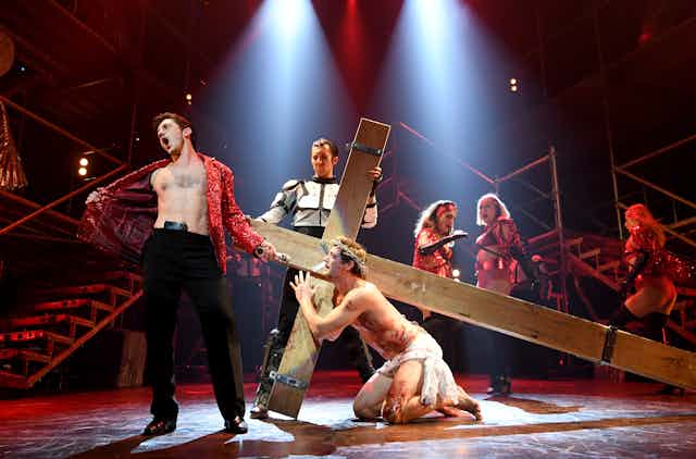 A musical theatre stage has a scene from Jesus Christ Superstar playing out on it