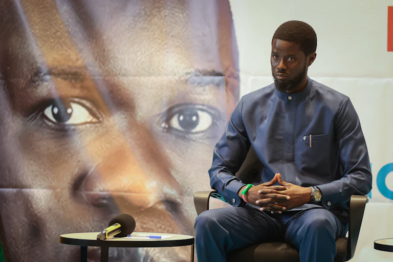 A seated man, with a large image of a face behind him