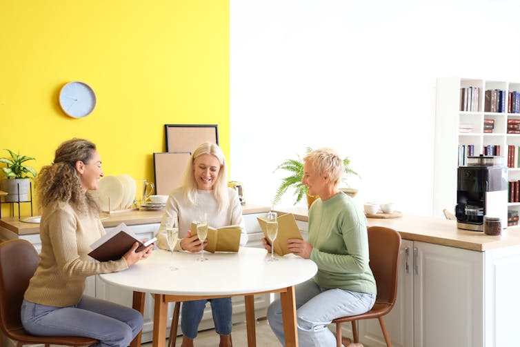 A group of women drinking wine and reading.