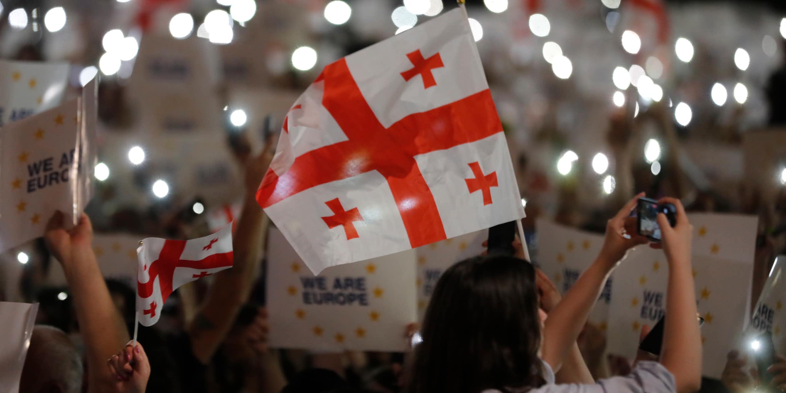 A crowd of people holding the Georgian national flag and placards reading: 'We are Europe".
