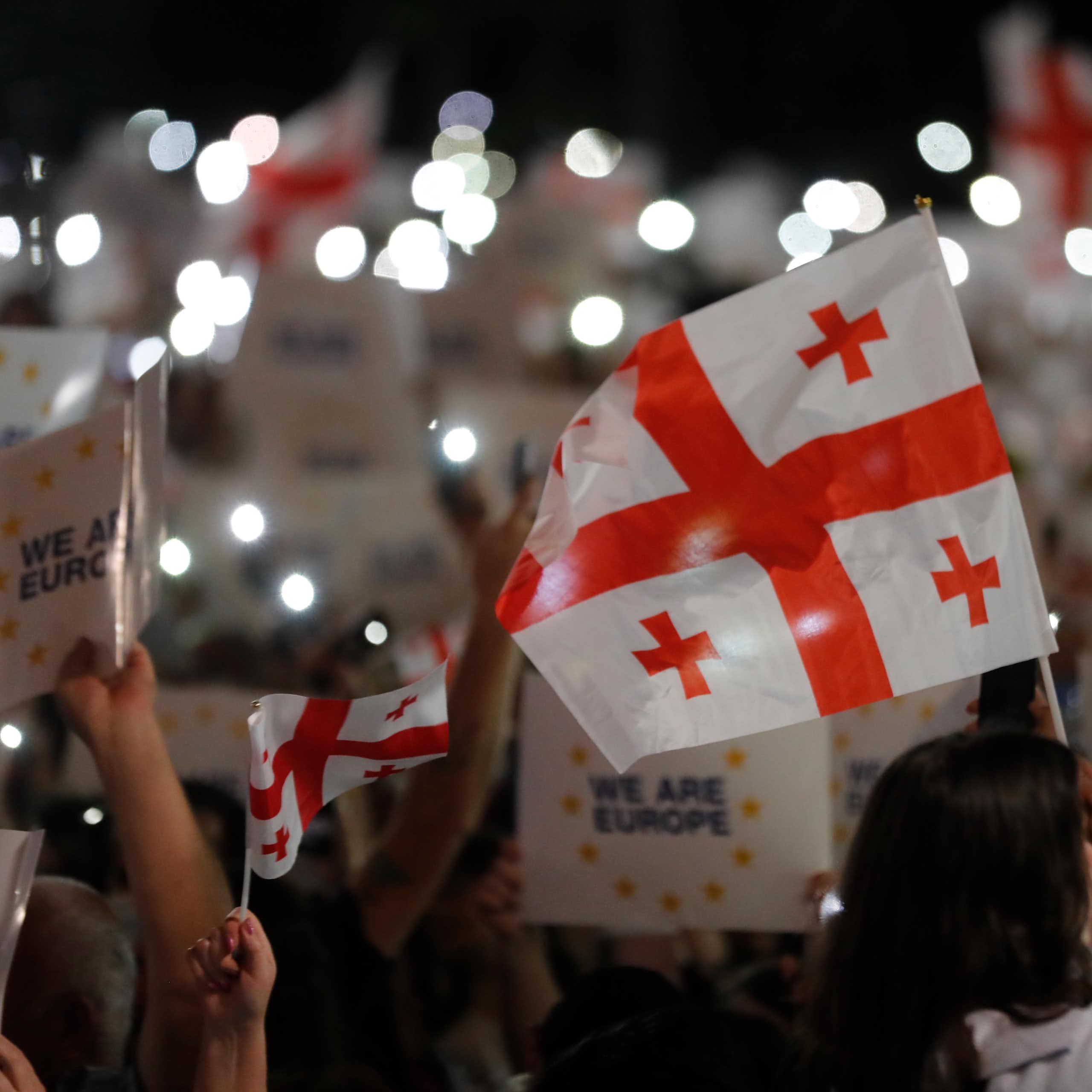 A crowd of people holding the Georgian national flag and placards reading: 'We are Europe".