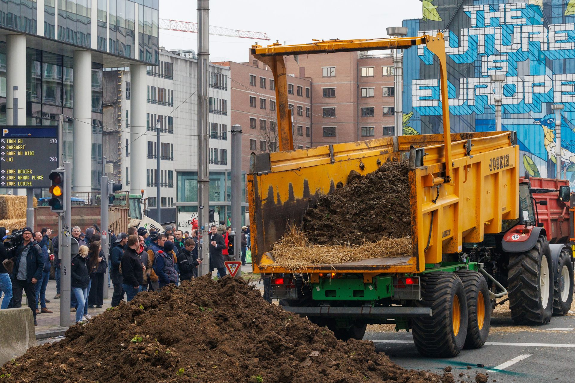 Farmers drop earth between flares lit by protesters on the side of an Agriculture and Fisheries Council in Brussels, Belgium, 26 March 2024.