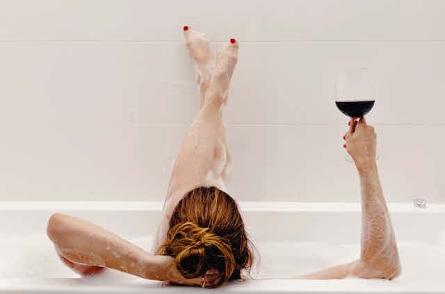 Woman relaxing in bath holding a glass of red wine