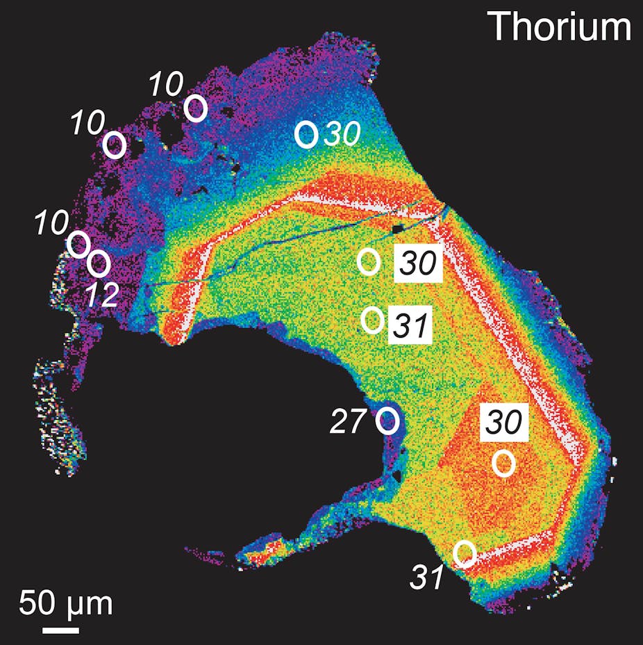Microscopy heat map of an oblong sliver, with violet at the edges and yellow toward its center, with numbers indicating millions of years superimposed.