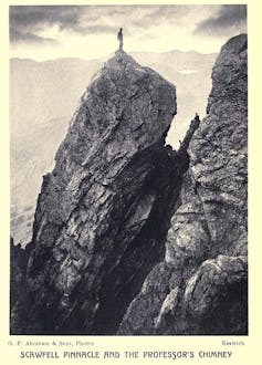 A man stood on top of a peak in a black and white photograph