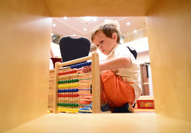A child seen playing with beads on an abacus.