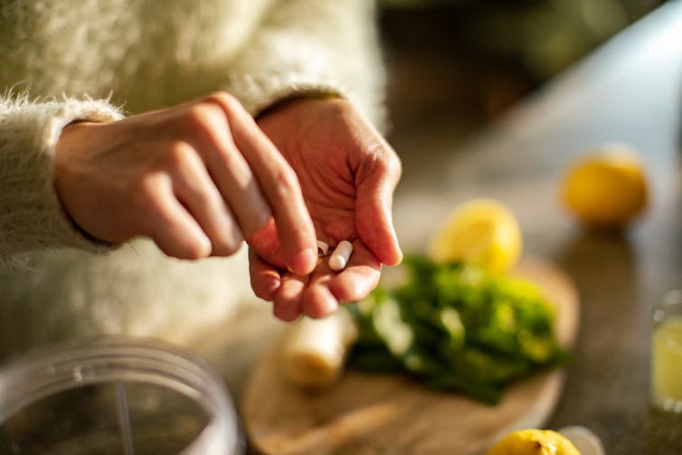 Someone takes a health supplement in a kitchen.