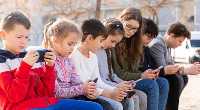 a row of children using mobile phones