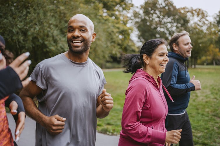 Group of people smiling and running in a park