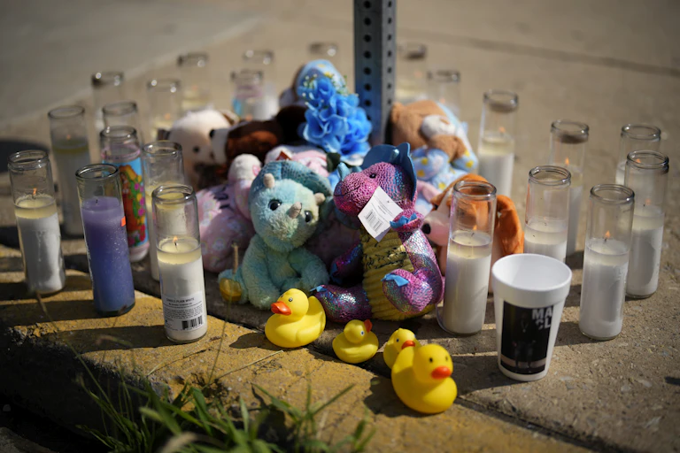 Stuffed animals and candles arranged on a Philadelphia sidewalk for victim of mass shooting.