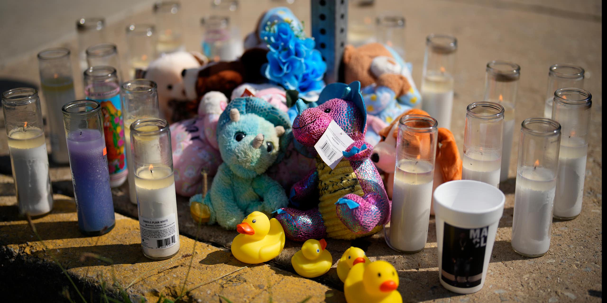 Stuffed animals and candles arranged on a Philadelphia sidewalk for victim of mass shooting.