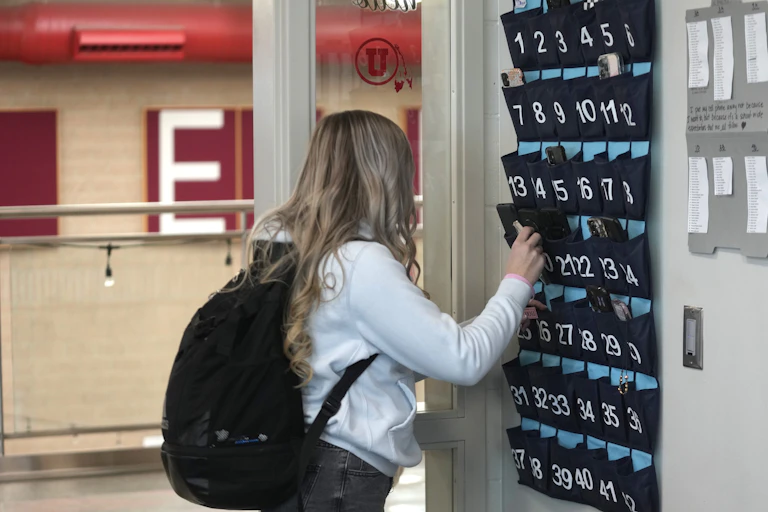 A student seen putting her phone into a wall holder.