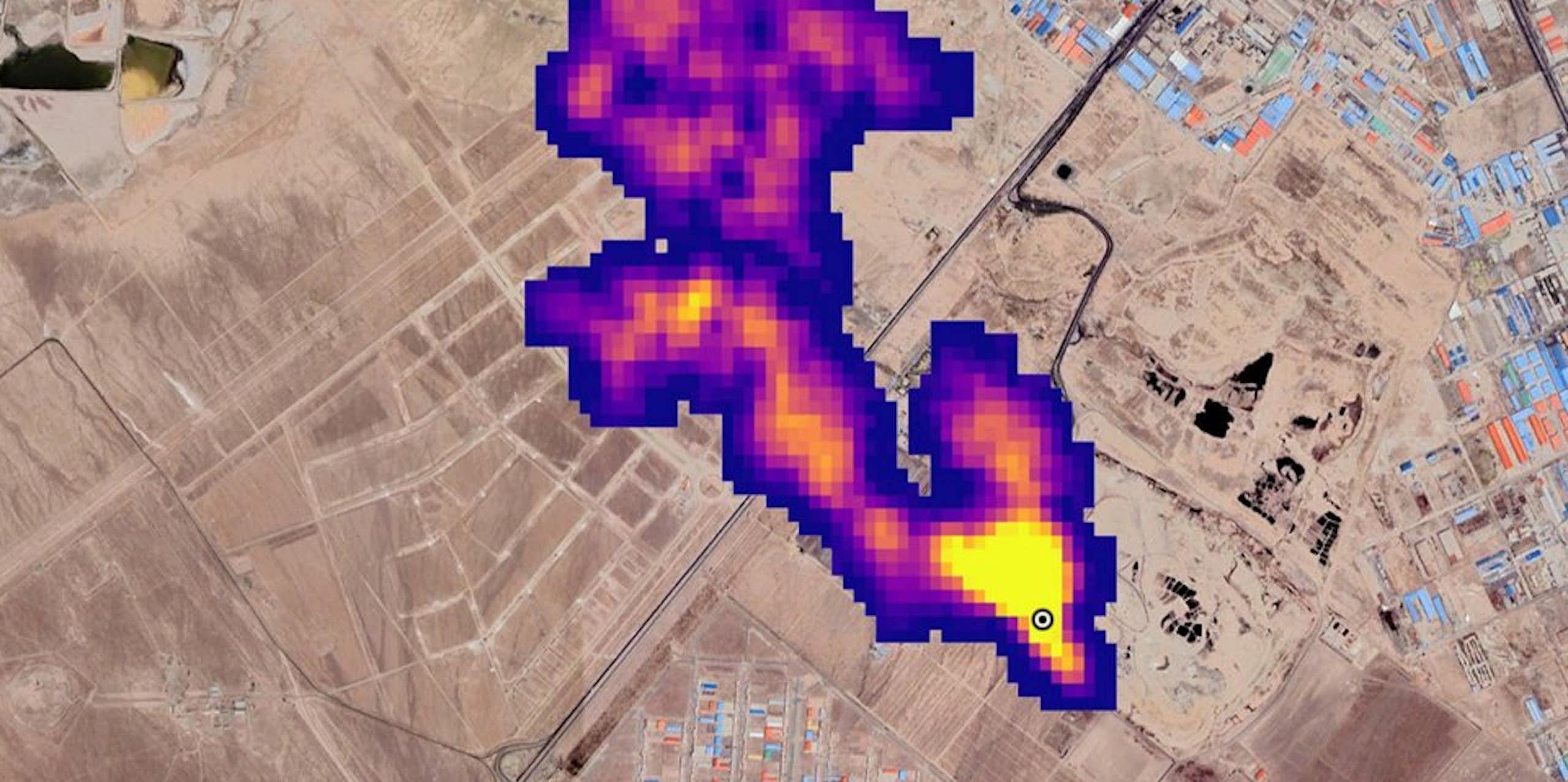 A colored image show methane leaking form a source with buildings nearby.