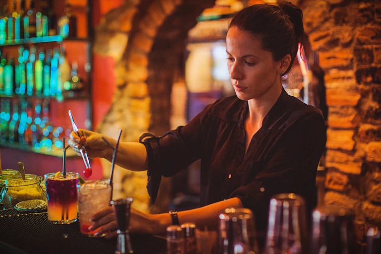 Female bar attendant adds cherry to a cocktail