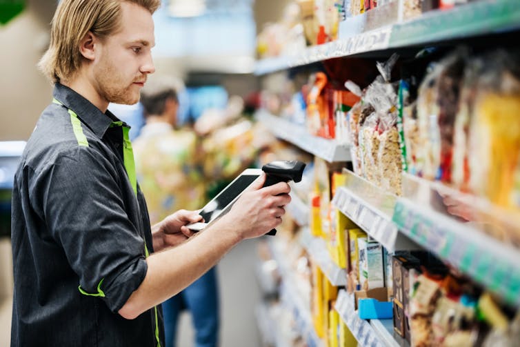 Man checks products on supermarket shelf