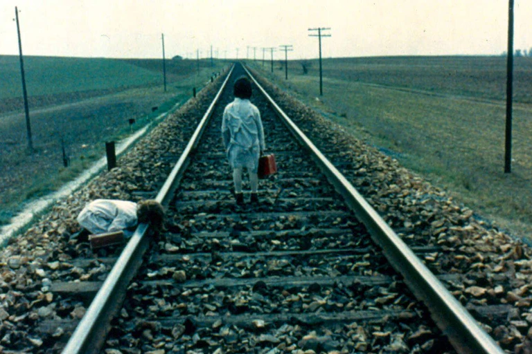 Two girls walk by a train track.