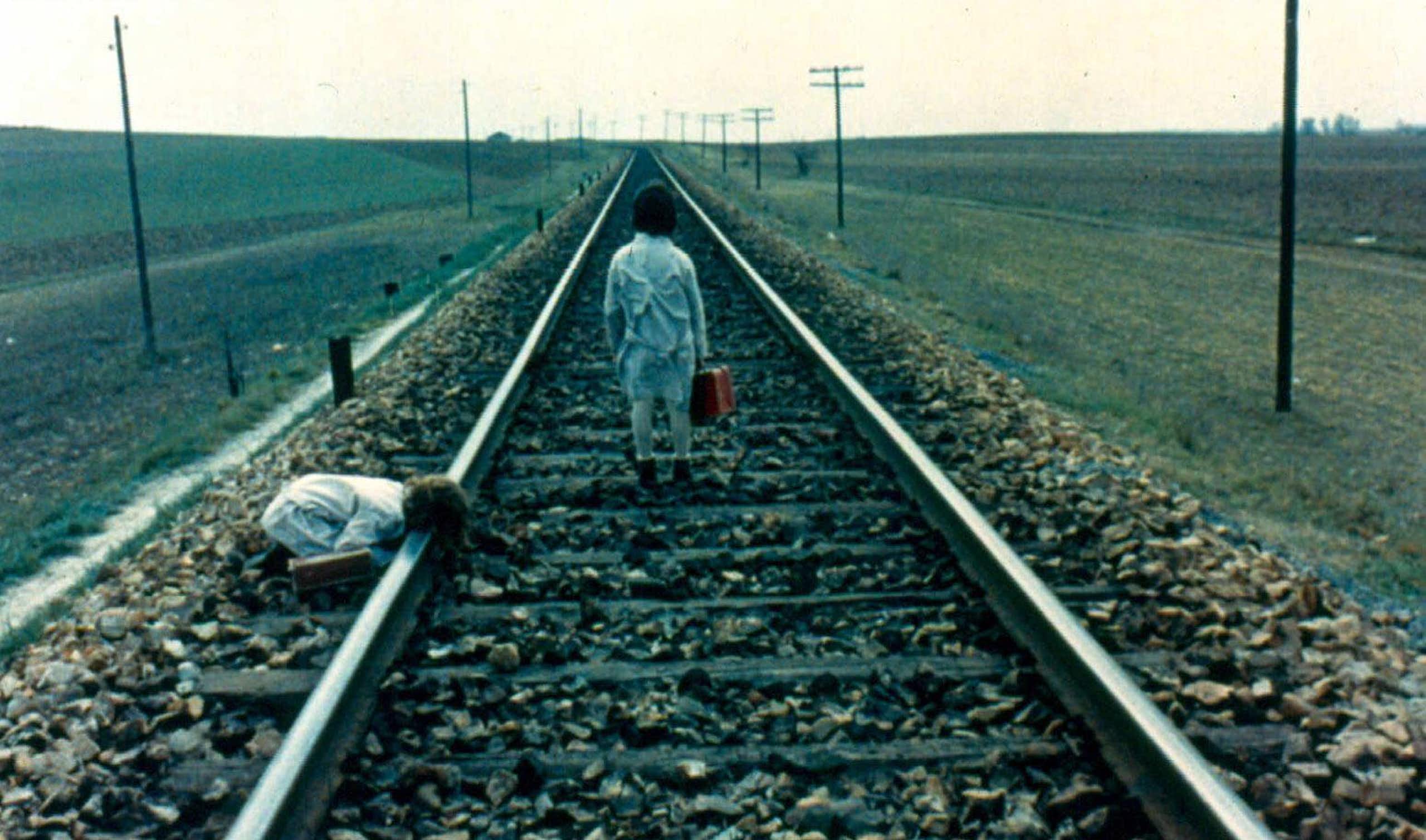 Two girls walk by a train track.