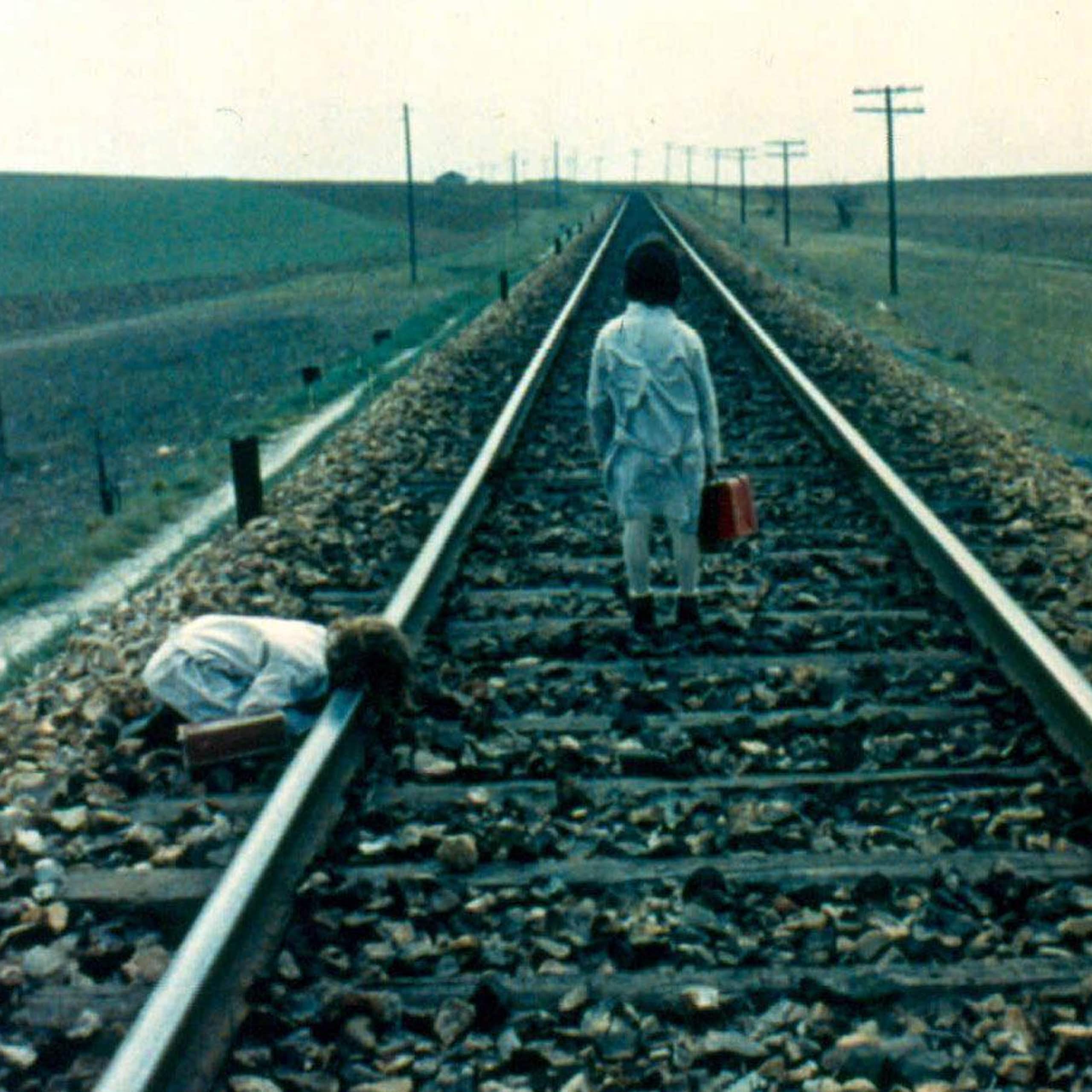 Two girls walk by a train track.