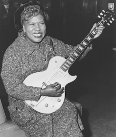 A woman seen holding guitar smiling.