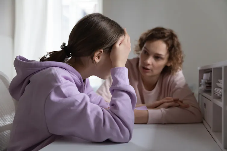 A woman sitting at a desk consoling another woman