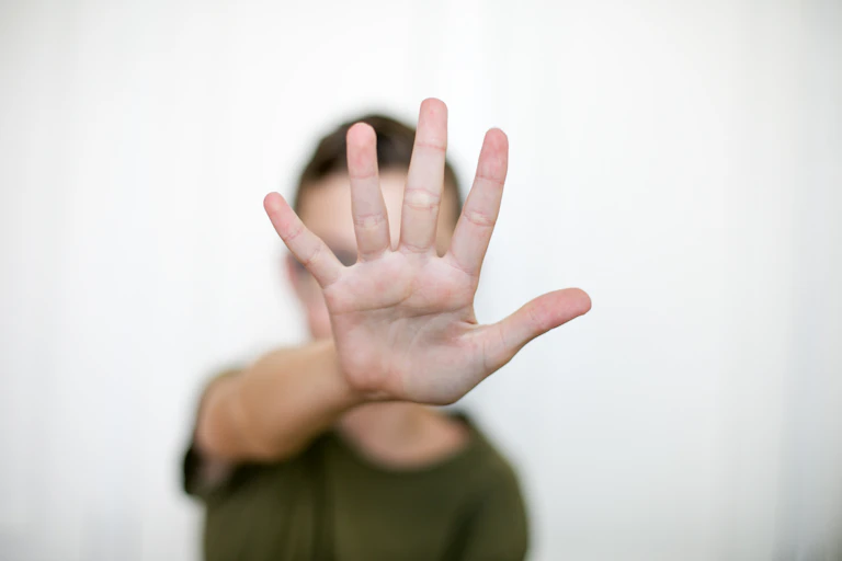 A person with an arm straight out, palm facing the camera, fingers extended.
