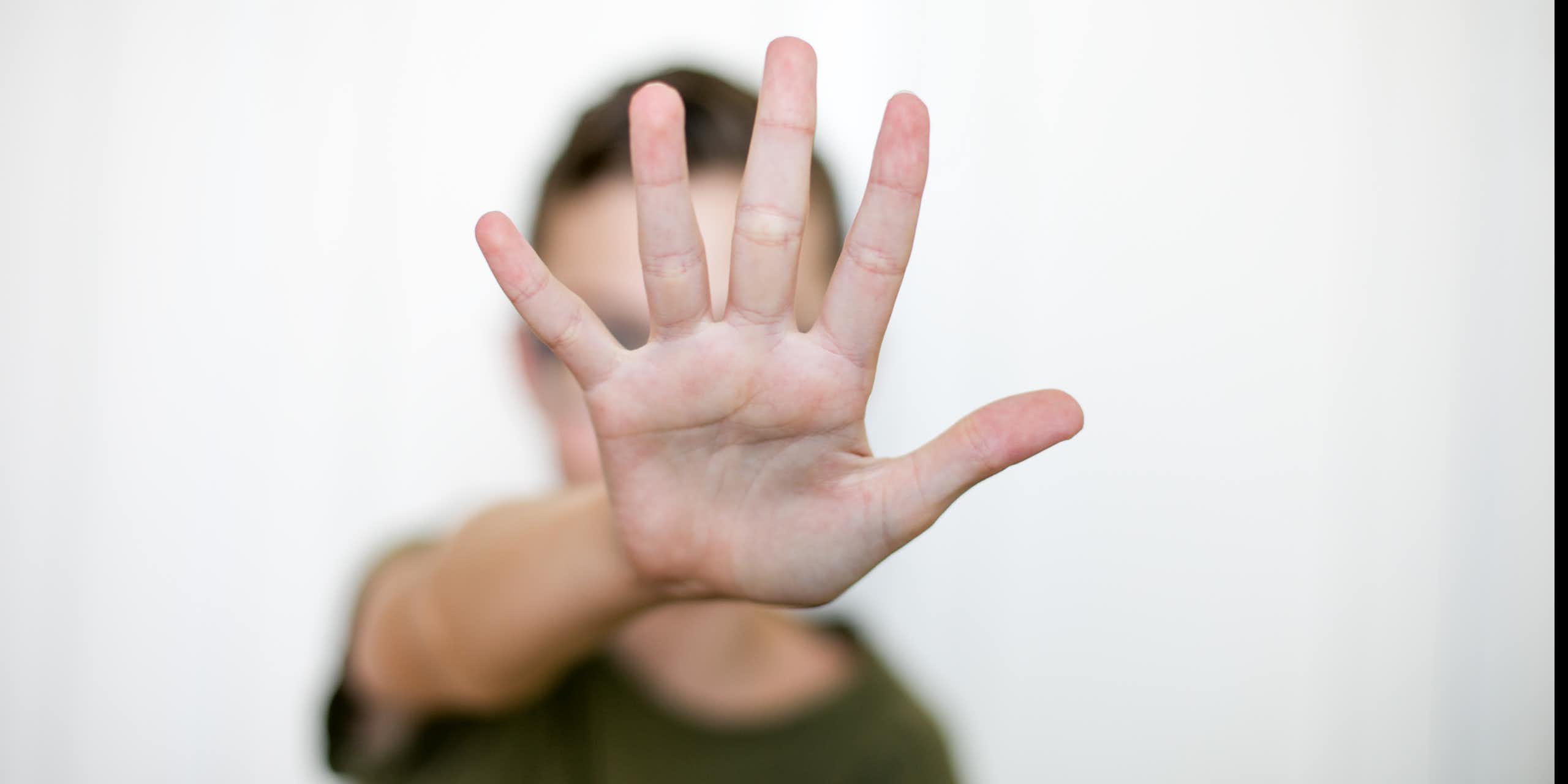 A person with an arm straight out, palm facing the camera, fingers extended.