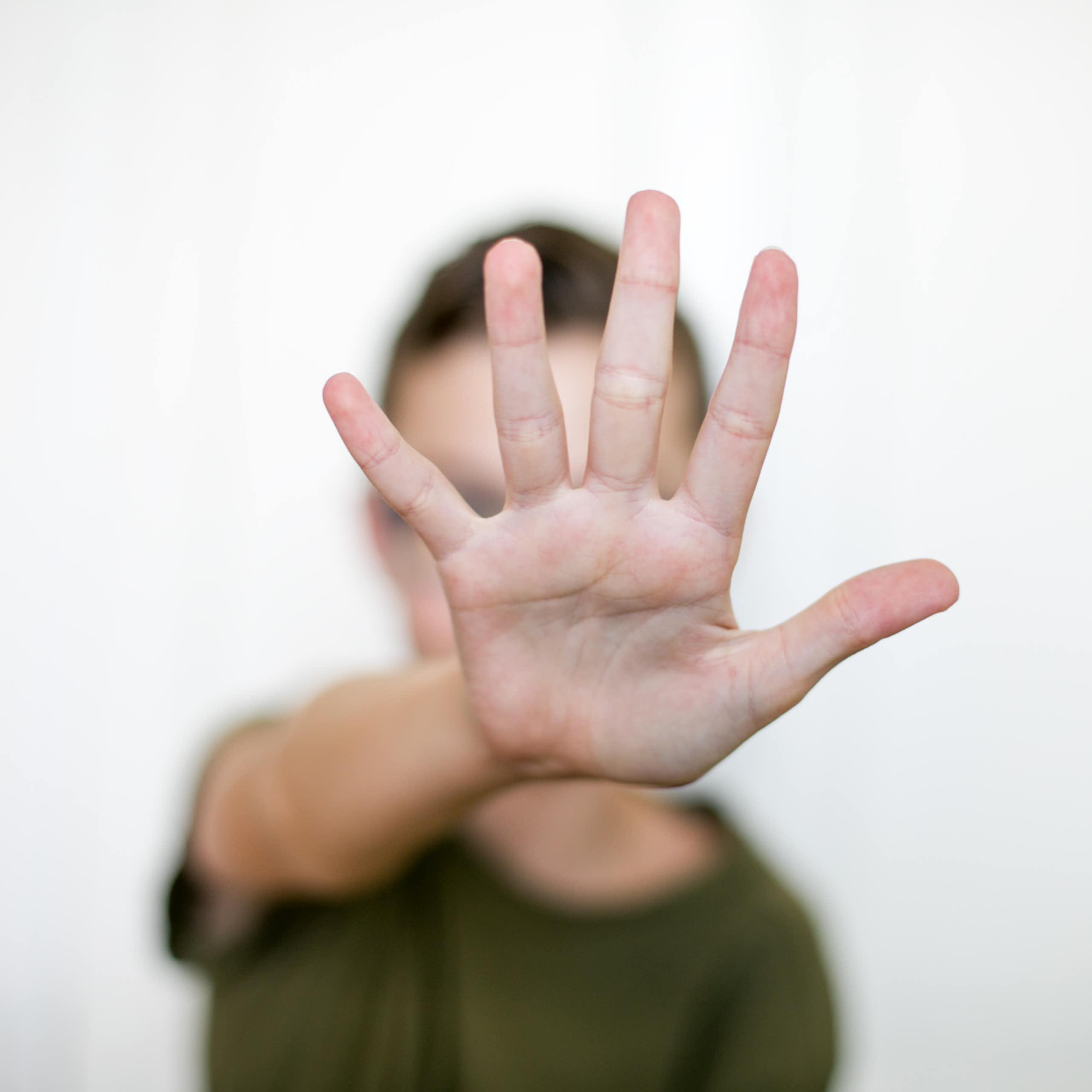 A person with an arm straight out, palm facing the camera, fingers extended.