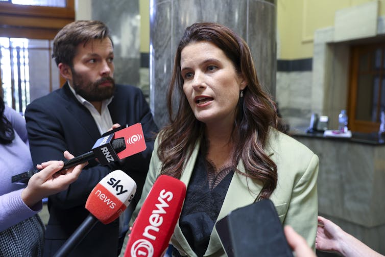 Nicola Willis in front of media microphones