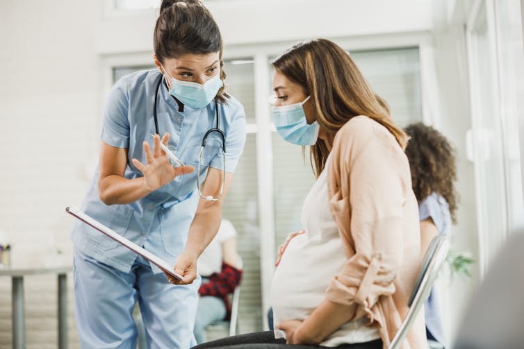 A pregnant woman talking to a nurse.