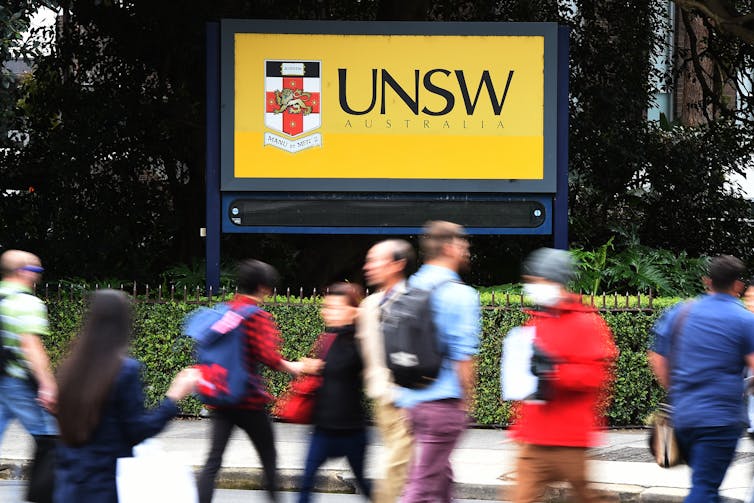 Pedestrians cross a road outside an entrance to the University of New South Wales.