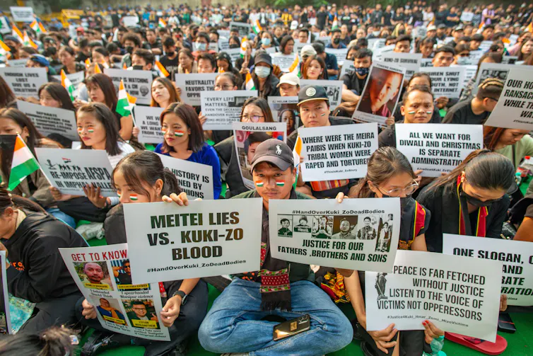 Hundreds of seated protesters holding banners