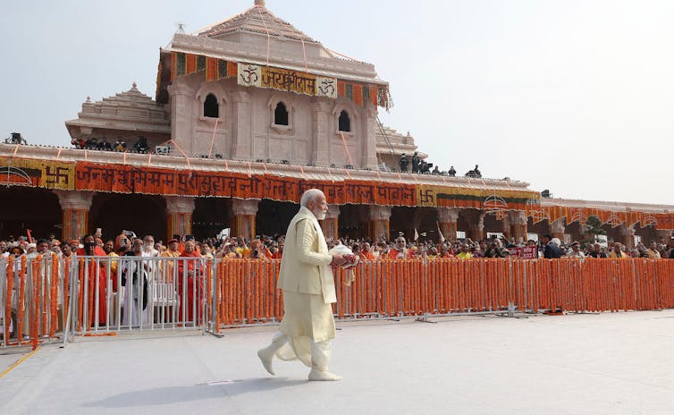 India's leader in a white suit walks past supporters in front of new Hindu temple