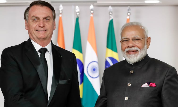 National leaders of Brazil and India stand together in front of their country's flags