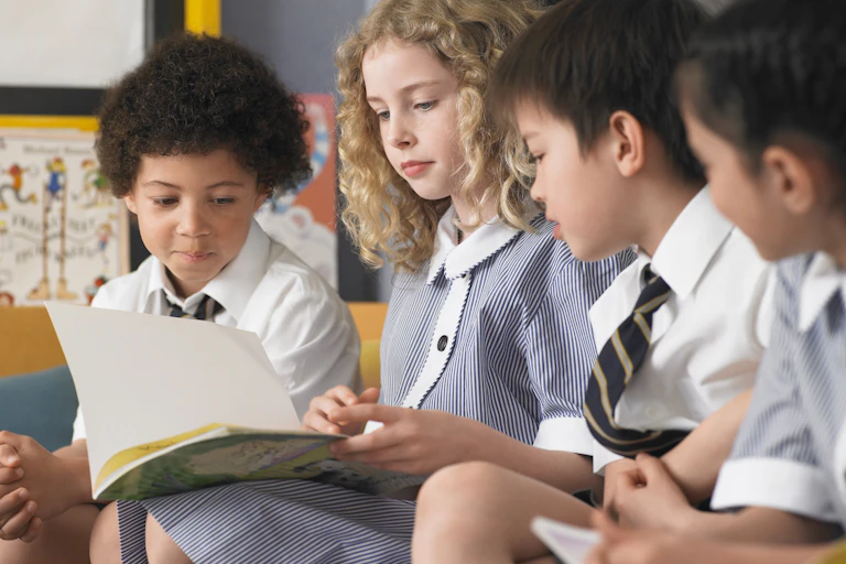 Children in school uniform looking at book
