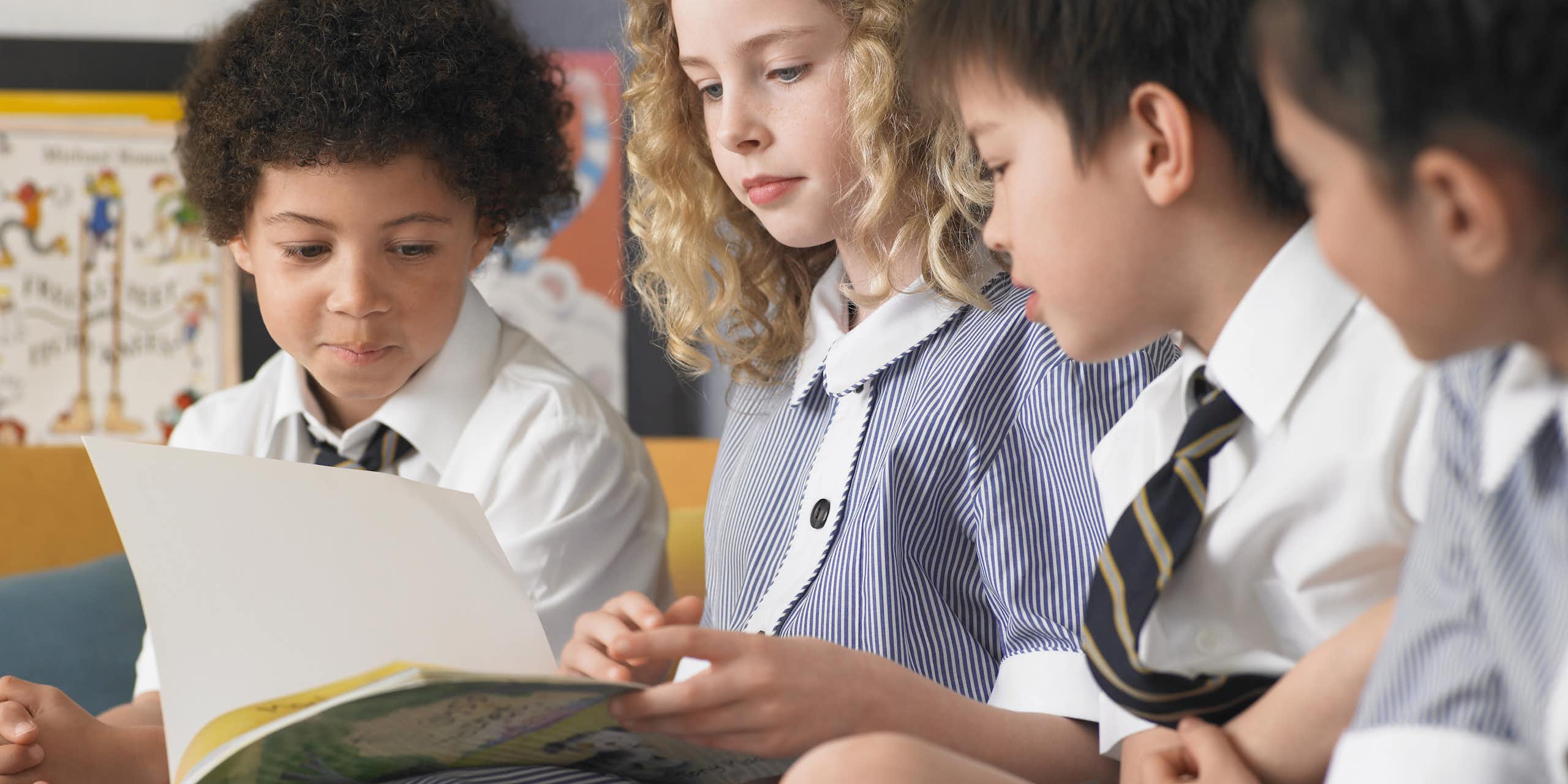 Children in school uniform looking at book