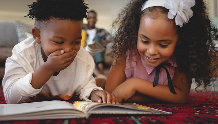 Boy and girl reading book together smiling