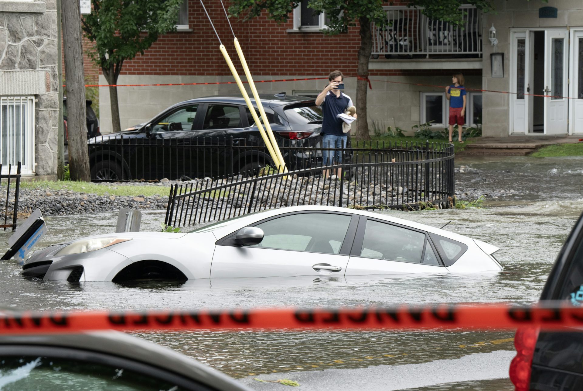 Une voiture est ensevelie sous l’eau, dans une rue résidentielle