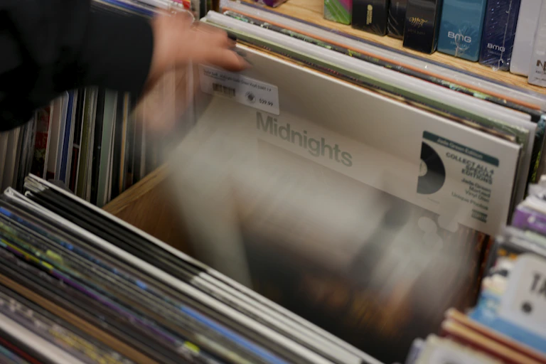 A hand seen flipping through records and the word 'midnights' is seen on one album.