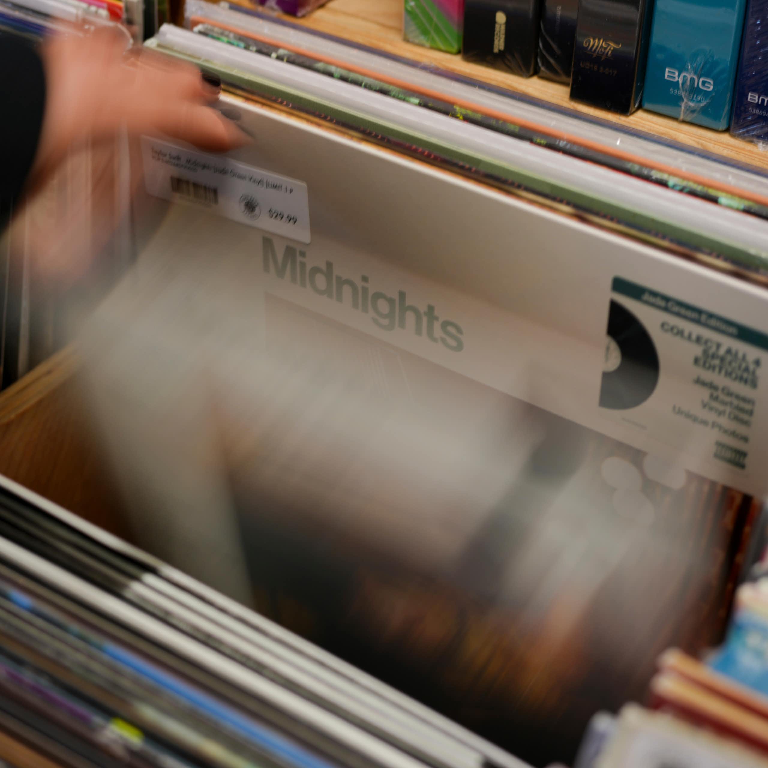 A hand seen flipping through records and the word 'midnights' is seen on one album.