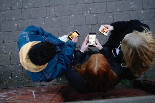 loking down on three young people who are looking at their phones