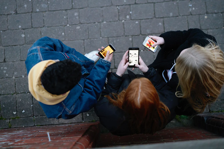 loking down on three young people who are looking at their phones