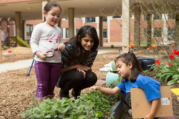A teacher with children at a garden.